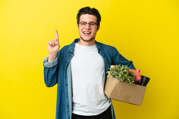 Russian Man making a move while picking up a box full of things isolated on yellow background...