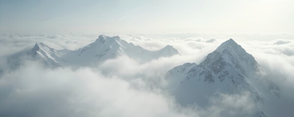 Obraz premium Snow covered mountain peaks emerge from thick clouds creating dramatic, awe-inspiring scenery. Soft light filters through atmosphere, revealing rugged terrain, vast sky. Majestic landscape evokes