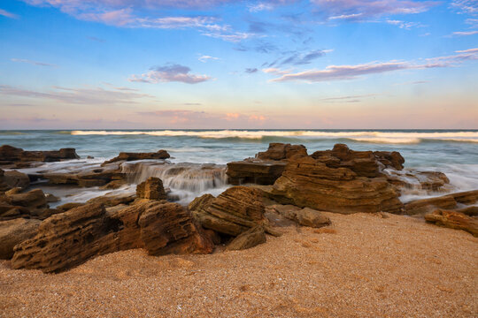 A beach of coquina rocks is sculpted by the sea in this evening landscape view with soft water at River to Sea Preserve