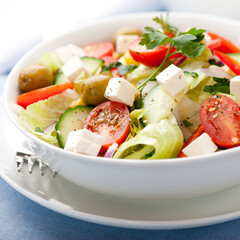 Fresh Mediterranean vegetable salad with feta cheese, tomatoes, olives, and crisp lettuce in a bowl