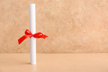 Diploma with red bow on beige background