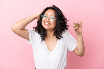 Young asian woman holding a Bitcoin isolated on pink background smiling a lot