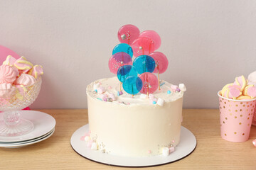 Cake with sweets for birthday party on table against white wall