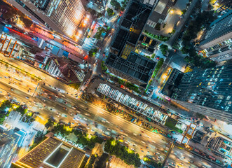 Aerial view of a huge city intersection with glowing traffic and illuminated skyscrapers at night.