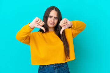 Young Ukrainian woman isolated on blue background showing thumb down with two hands