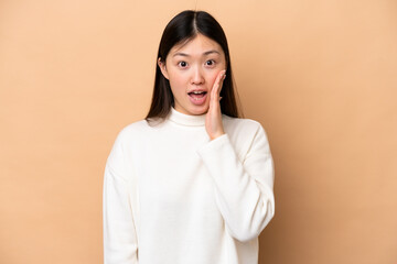 Young Chinese woman isolated on beige background with surprise and shocked facial expression