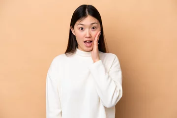  Young Chinese woman isolated on beige background with surprise and shocked facial expression © luismolinero