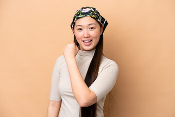 Young Chinese woman isolated on beige background celebrating a victory