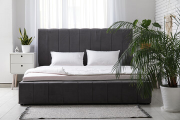 New orthopedic mattress with blanket on stylish bed in room