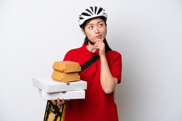 Young Chinese delivery woman taking takeaway food isolated on white background having doubts