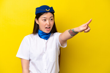 Airplane Chinese woman stewardess isolated on yellow background pointing away