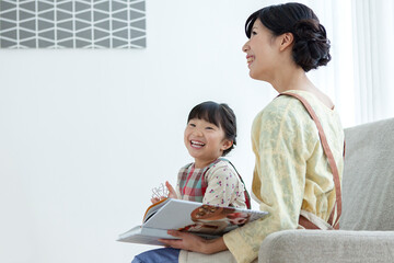 ソファで本を見るエプロン姿の親子
