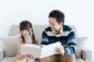ソファで本を見る親子