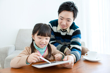 リビングをタブレットを見る親子