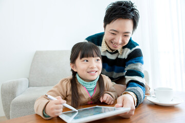 リビングをタブレットを見る親子