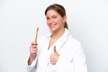 Young caucasian woman brushing teeth isolated on white background with thumbs up because something...