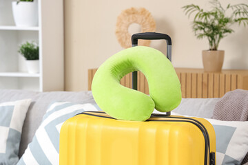 Yellow suitcase and neck pillow in room. Travel concept