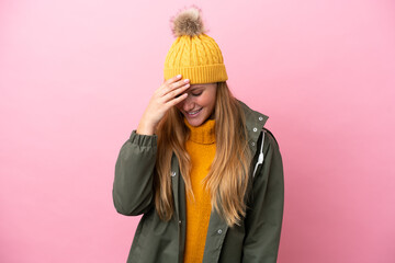 Young blonde woman wearing winter jacket isolated on pink background laughing