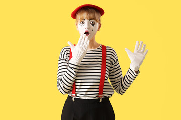 Surprised female pantomimist on yellow background