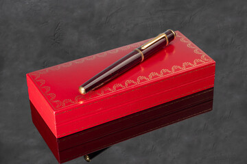 Fountain pen with box on dark gray background. Stationery branded items