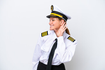 Airplane caucasian pilot woman isolated on white background listening to something by putting hand...