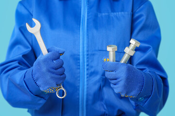 Mechanic with bolts and wrench on blue background, closeup