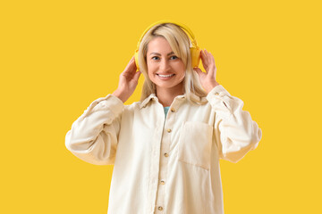 Beautiful woman in headphones on yellow background