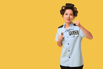 Female Asian police officer with hair curlers on yellow background