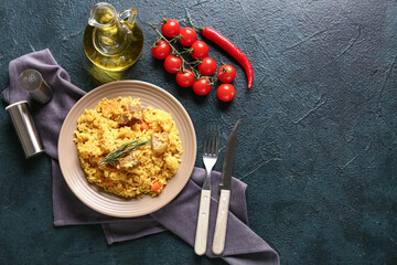 Plate of tasty pilaf with chili pepper and cherry tomatoes on dark background
