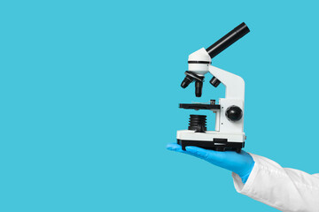 Male scientist with microscope on blue background, closeup