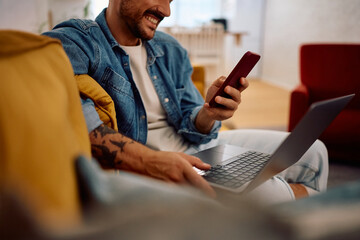 Close up of using smart phone while working on laptop at home.