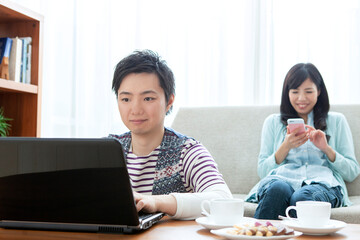 リビングでパソコンを見る夫婦