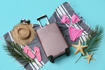 Composition with suitcase, swimsuit, photo camera and beach accessories on blue background