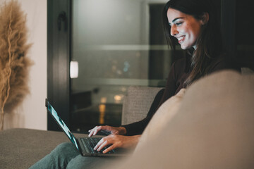 Young woman alone at home working late at night on her laptop. Freelancing, studying, chatting...