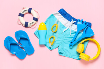 Composition with swimming trunks, bottle of sunscreen cream and beach accessories on pink...
