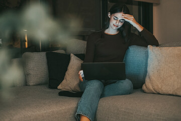 Young woman alone at home working late at night on her laptop. Freelancing, studying, chatting...