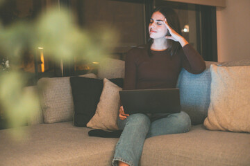 Young woman alone at home working late at night on her laptop. Freelancing, studying, chatting...