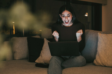 Young woman alone at home working late at night on her laptop. Freelancing, studying, chatting...