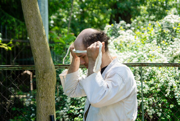 Man in martial arts uniform putting on a white blindfold outdoors, focusing on preparation or training. Represents discipline, challenge, and sensory deprivation practice.