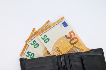 Money sticking out of a wallet lying on a white background, euro banknotes, minimum wage in the...
