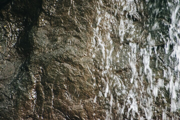 Cascading water flows down dark, textured rock in an Indian national park.