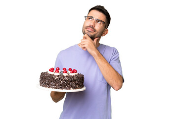 Young caucasian man holding birthday cake isolated on green chrome background looking up while...