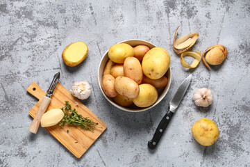 Bowl of raw baby potatoes with garlic and thyme on grey background