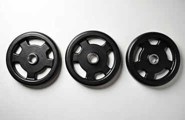 Three black weight plates arranged on clean white surface. Circular metal discs feature minimalist design with cutouts for grip, ideal for strength training, fitness enthusiasts. Essential gym