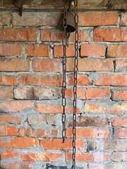 old brick wall, there is a rusty chain and a rusty bell hanging on the wall of the barn