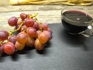 Beautiful juicy pink grapes on a cutting board, next to a cup of freshly squeezed juice
