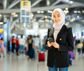 Muslim asian businesswoman traveler holding boarding pass ticket, passport and smartphone at the...