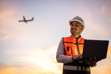 Smart engineer wearing safety uniform working with tablet near airport at night. Maintenance...