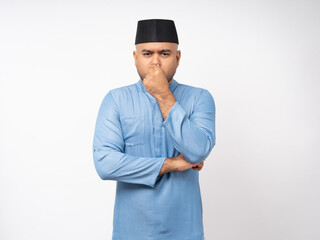 Bad smell stinks. Asian muslim man standing pinching nose with disgust. Holding breath with fingers on nose on isolated background.
