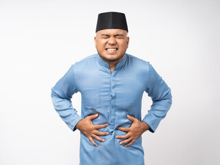 Asian muslim man had a stomach ache and gastritis. Islamic man put hand on his stomach and squeezed it to relax and soothe has go to toilet need to poop. Shot on isolated white background.